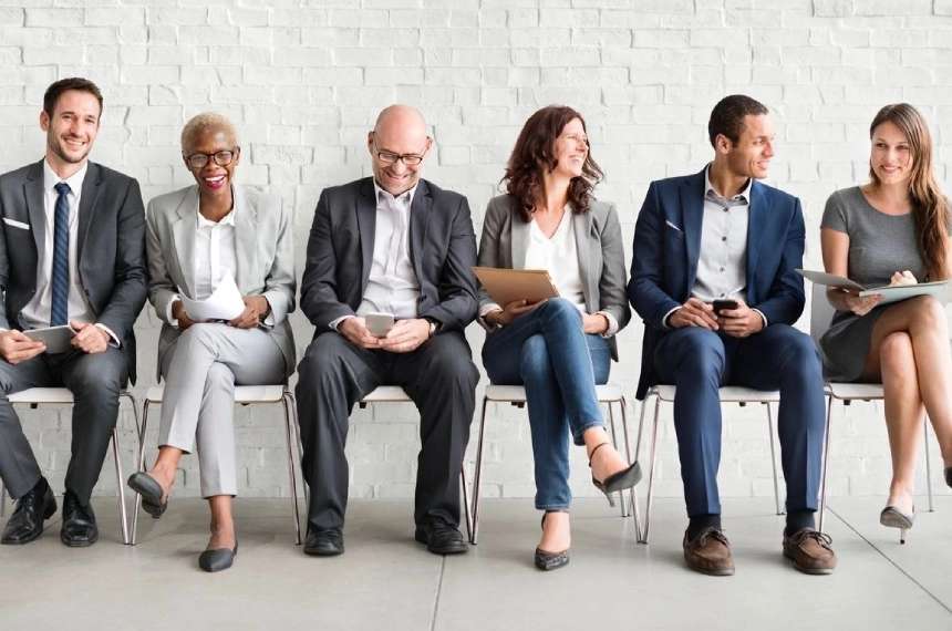 A group of people sitting on chairs in front of a wall.
