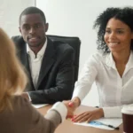 A woman shaking hands with another person at a table.