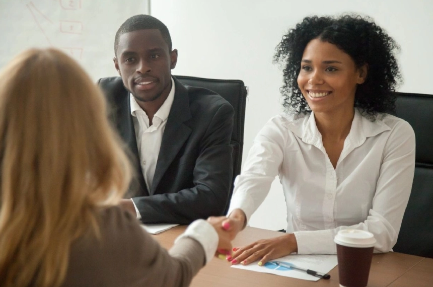 A woman shaking hands with another person at a table.