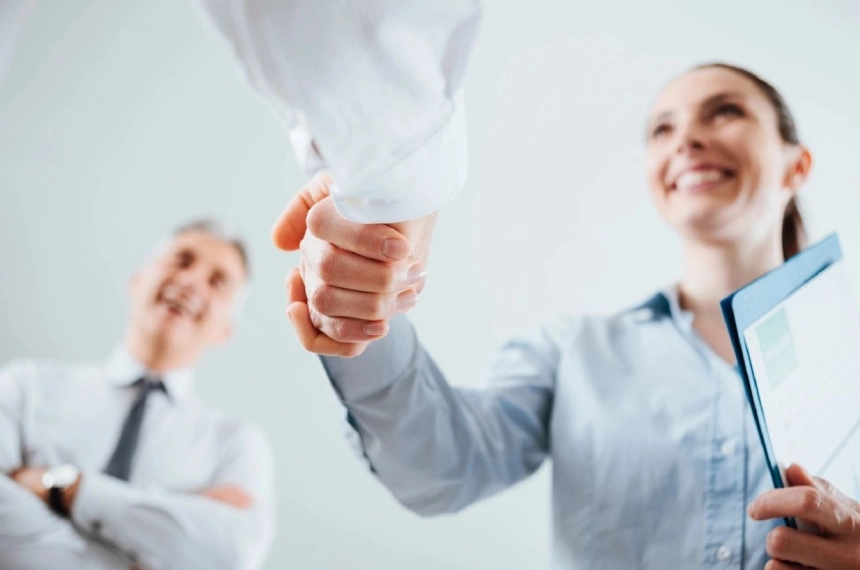 Two people shaking hands in a room.