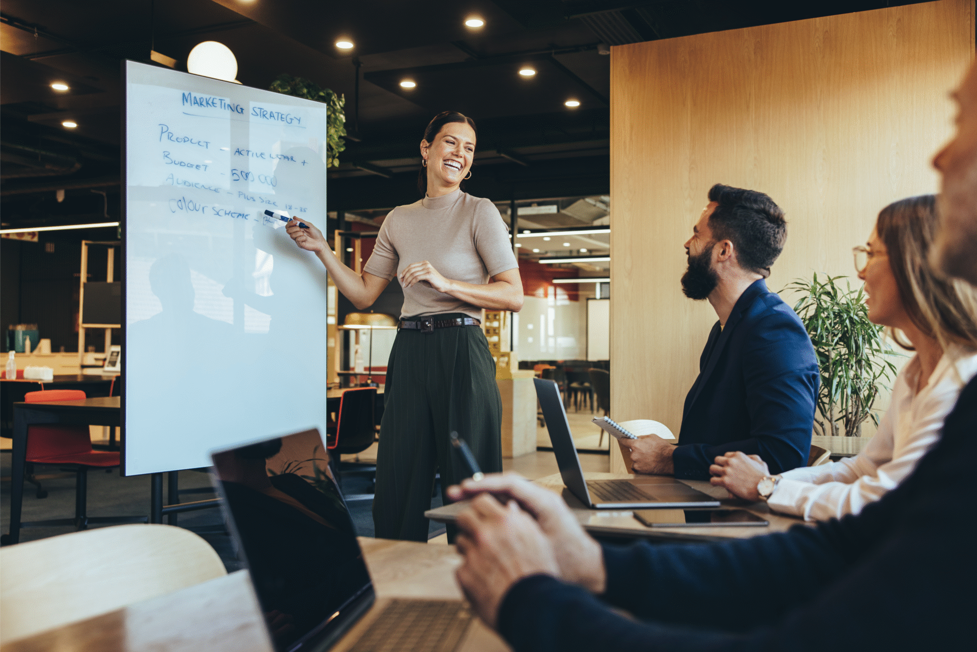 Woman presenting strategy on whiteboard to colleagues