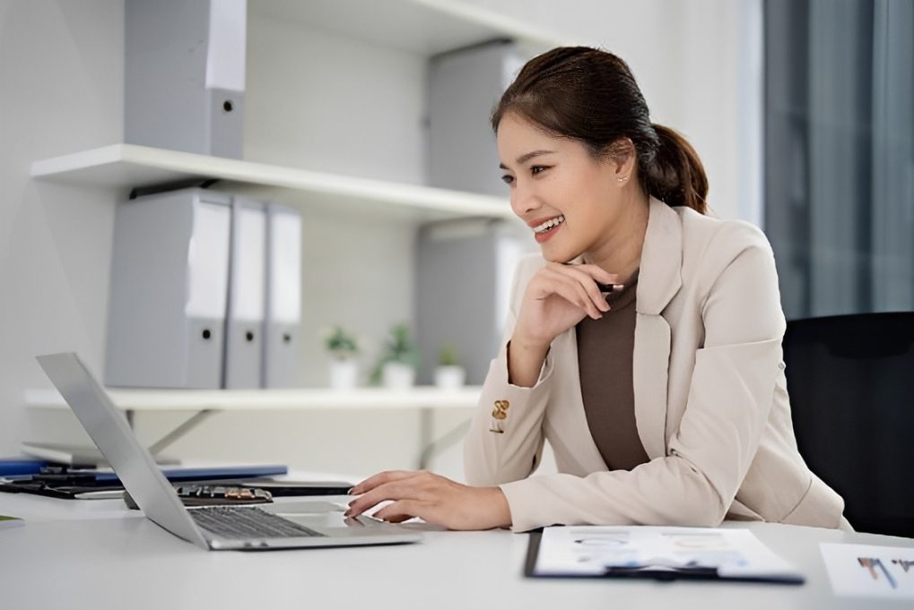 Smiling businesswoman working on laptop at desk